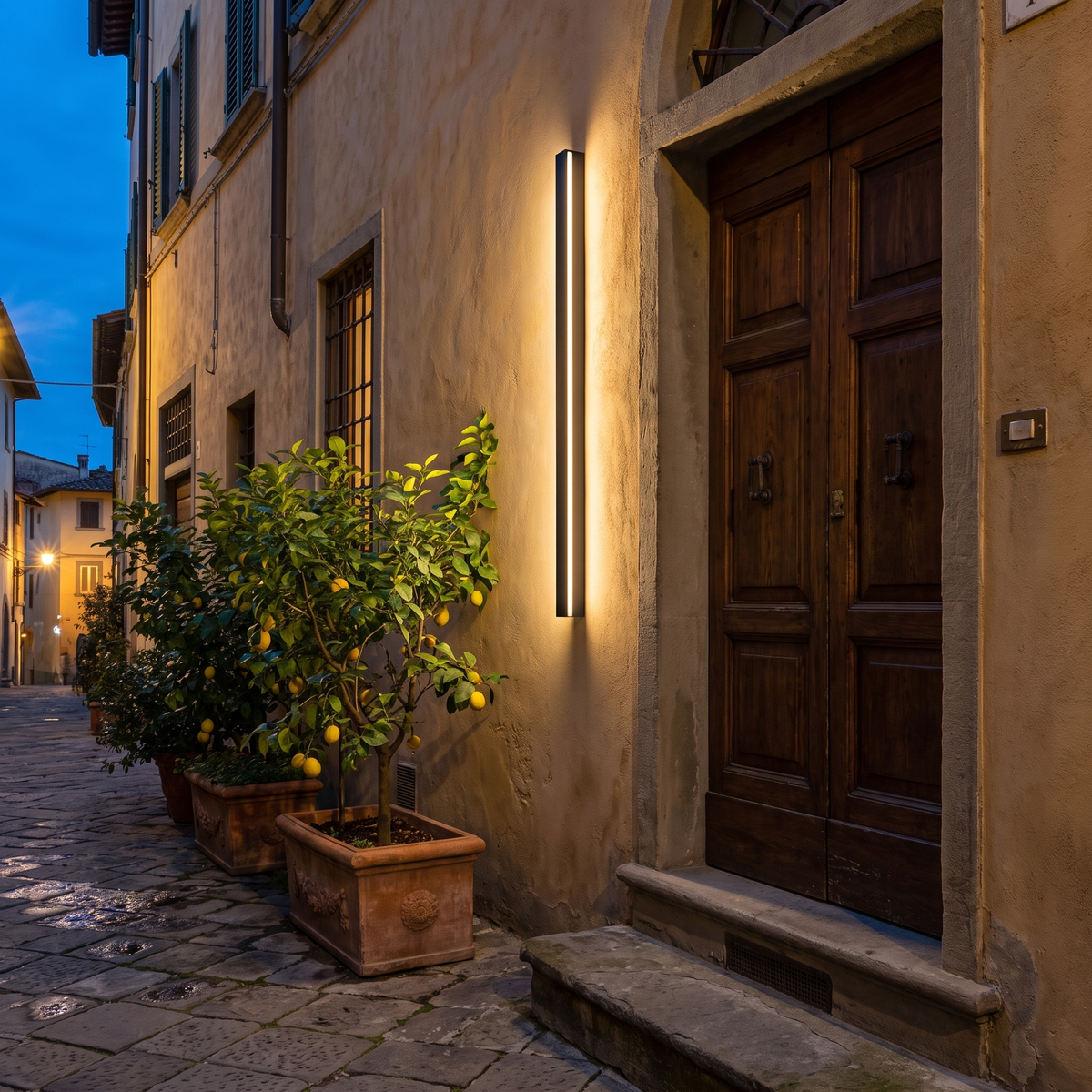Black linear wall sconce beside an Italian townhouse front door